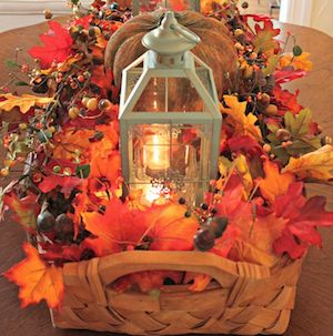 woven basket with fall leaves and berries with a lantern in the middle 