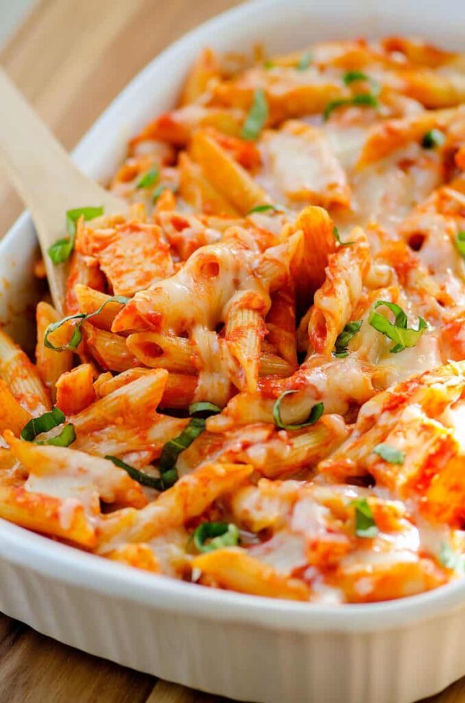 Kid friendly chicken parmesan casserole being spooned out of a white baking dish