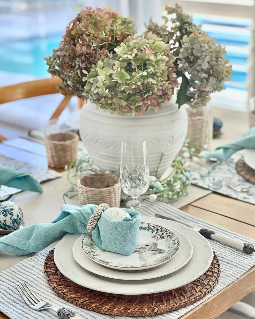 Easter Tablescape ideas, clever blue napkin folded into bunny ears around and egg. hydrangea centerpiece.