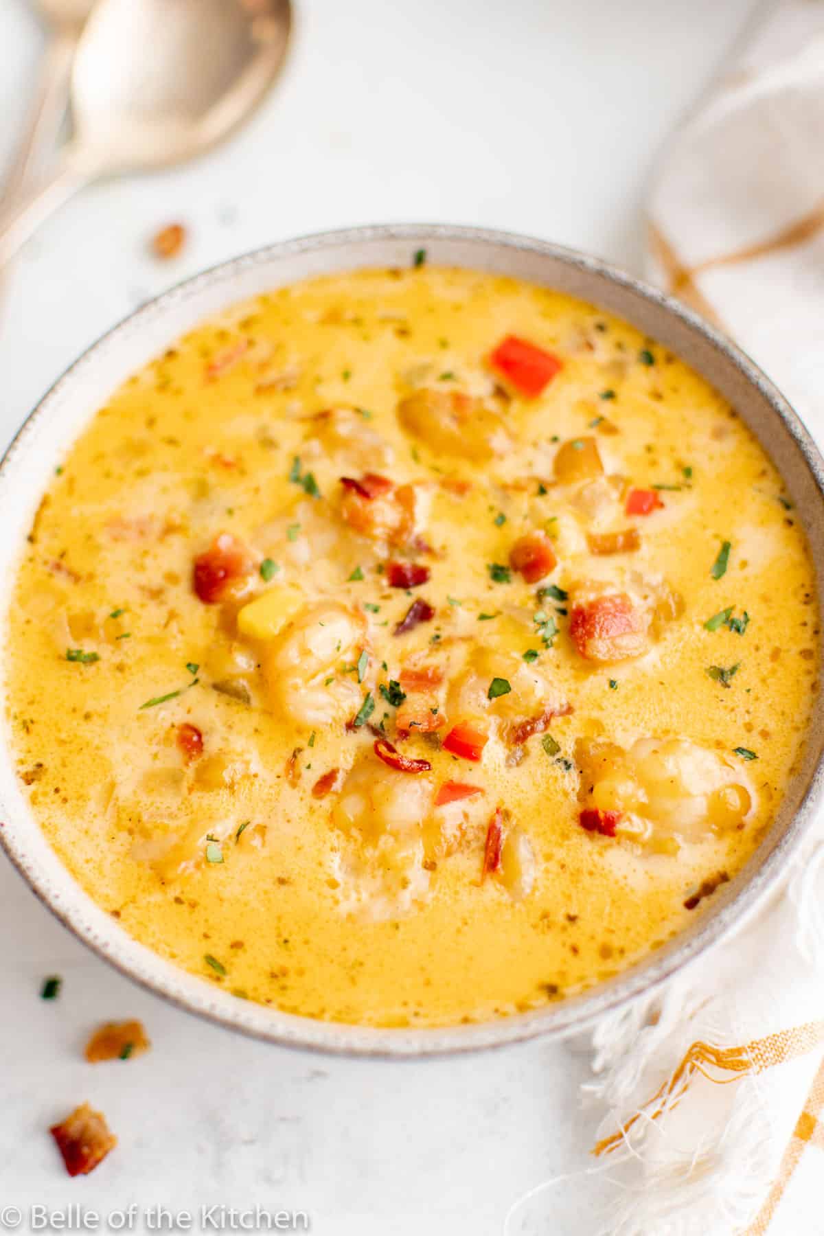 Bowl full of shrimp and corn chowder with spoons in background.